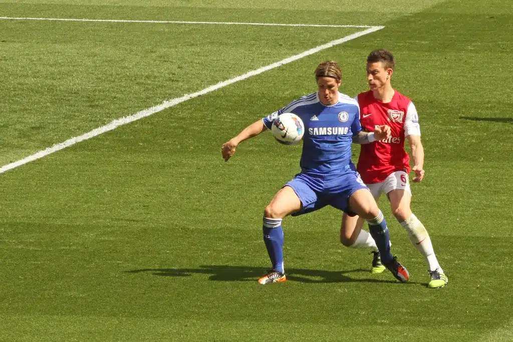 Fernando Torres i et blåt Chelsea-sæt kontrollerer en fodbold med Laurent Koscielny bag sig.
