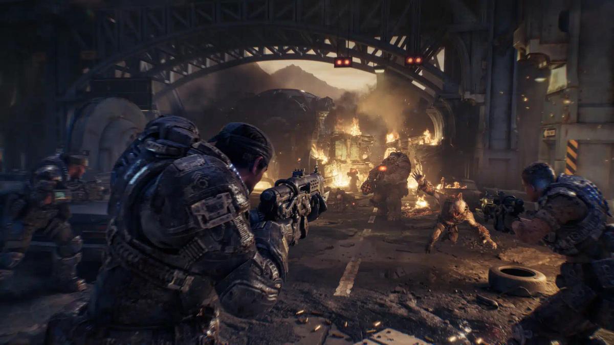Soldater i tung rustning i kamp mod monstre i et ødelagt bymiljø fra Gears of War: E-Day.